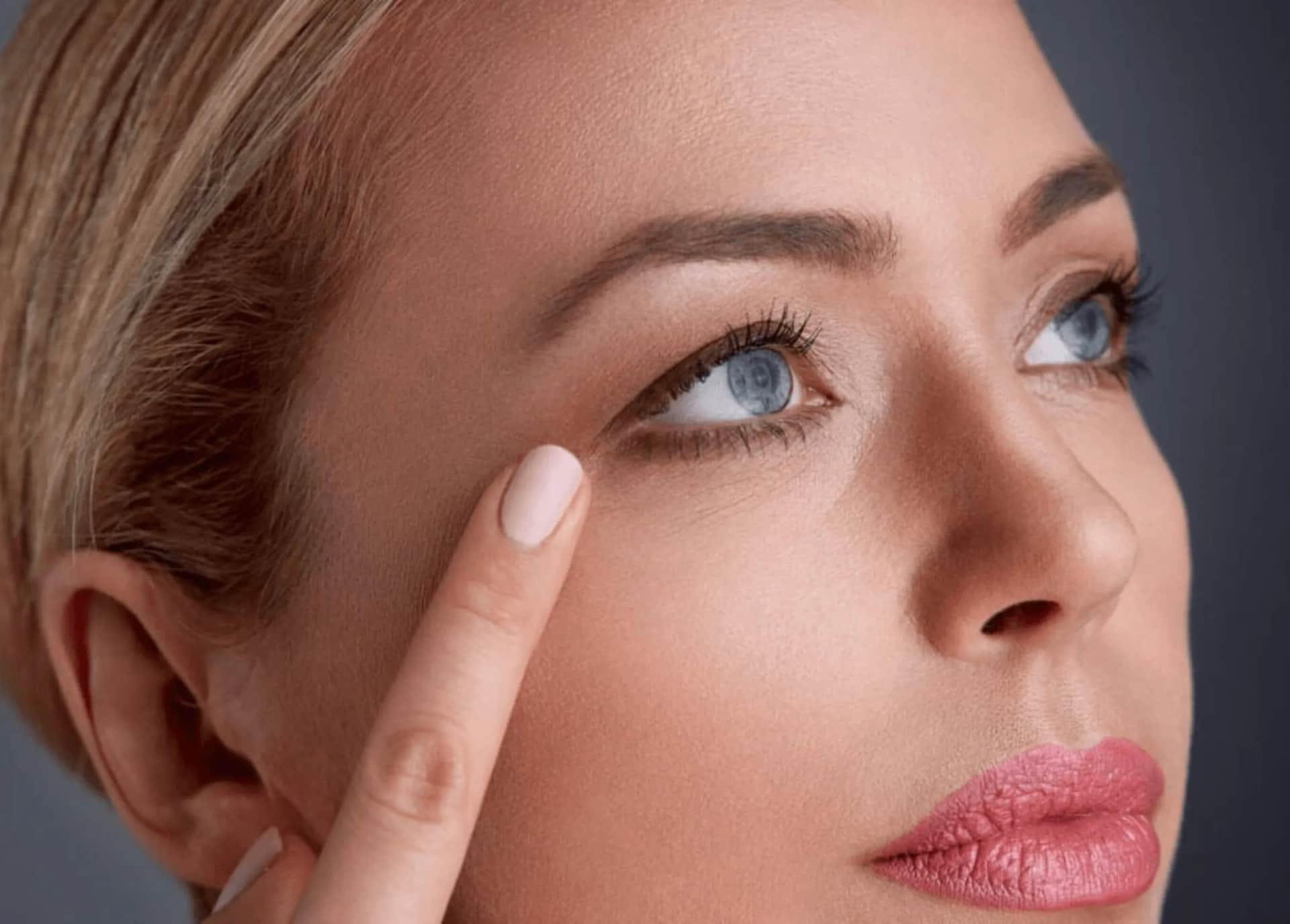 Ethnic Rhinoplasty in Plano TX: Side profile of blonde woman with blue eyes pointing at her eyes