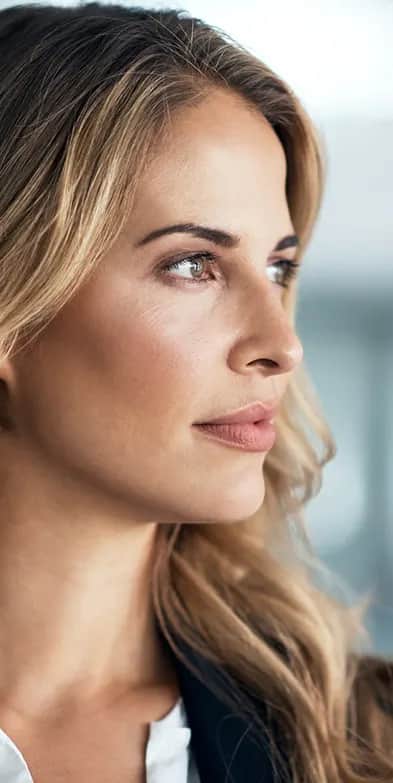 A woman looking confidently out a window in a professional setting.