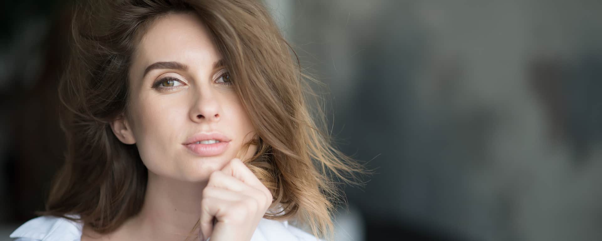 Woman touching nose and jawline showing facial profile before deviated septum surgery consultation in Plano and Dallas