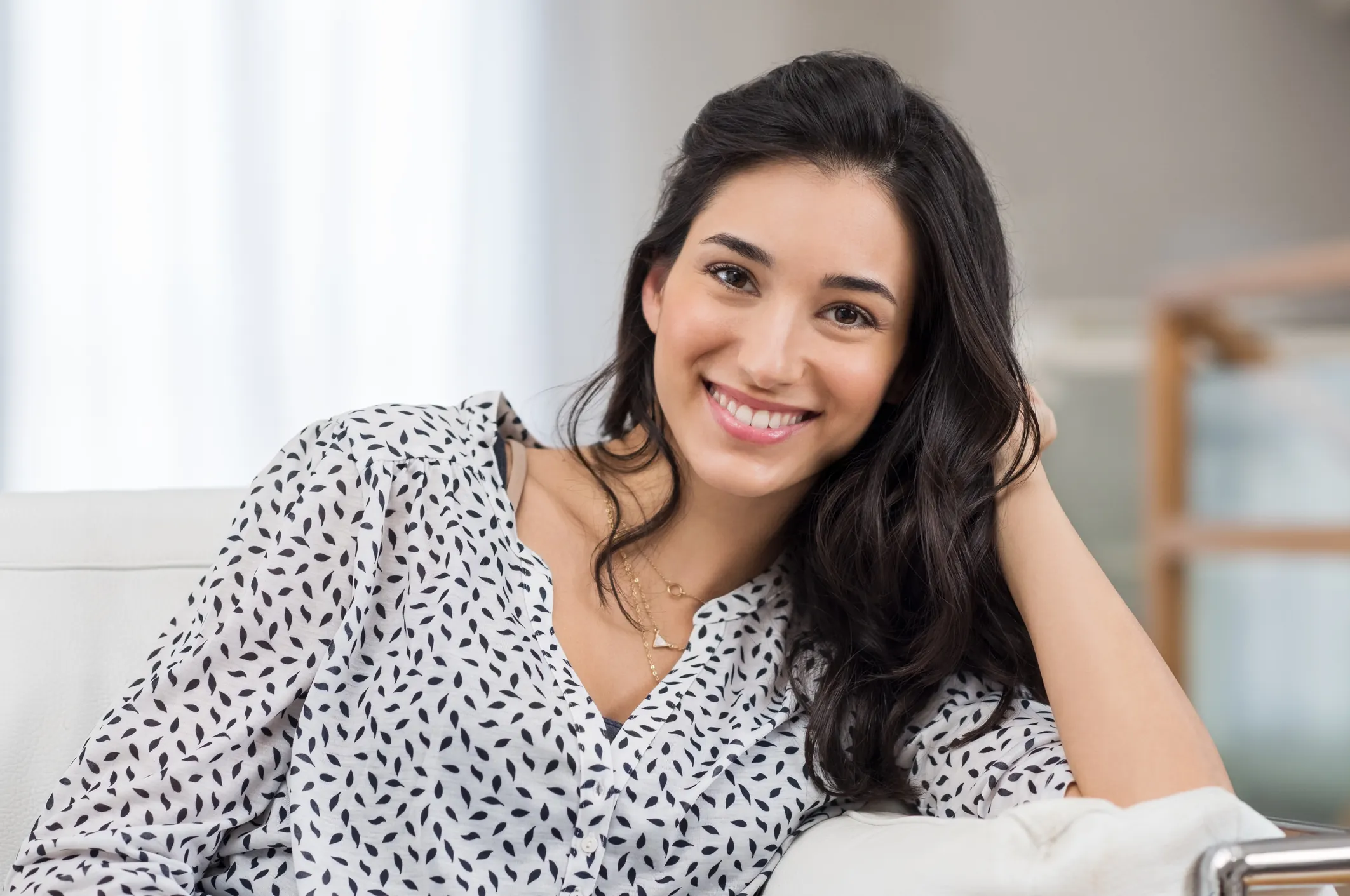 Nasal Reconstruction: A smiling woman in a striped blouse resting her head on her hand.