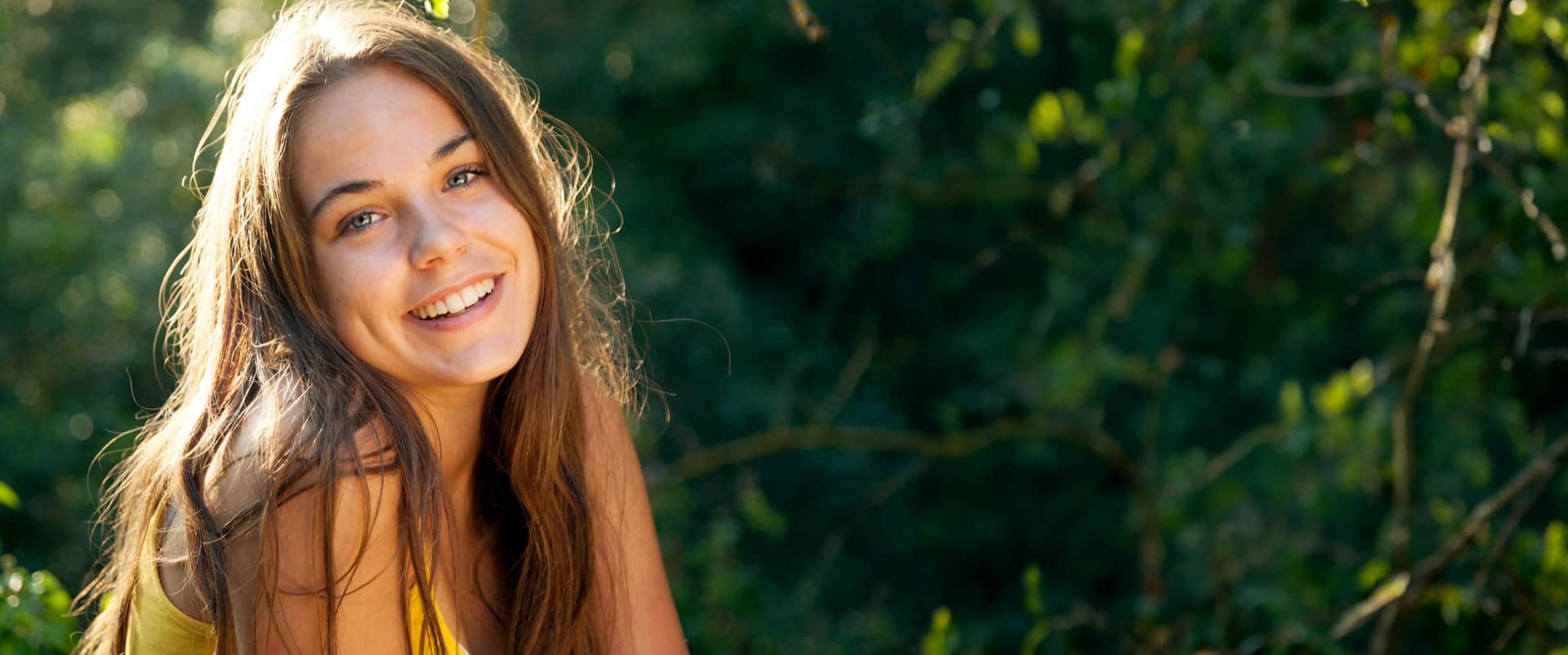 Teen rhinoplasty: Smiling teenage girl outdoors with natural facial features and confident expression