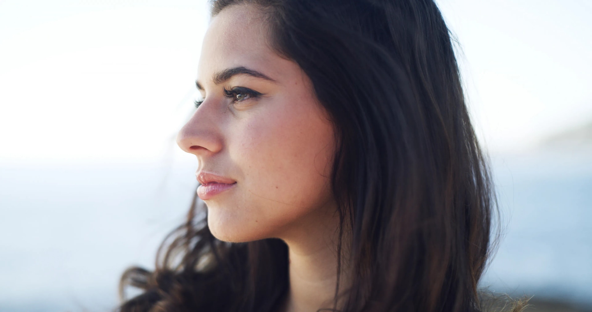 Nasal Reconstruction: A close-up profile view of a young woman with a naturally contoured nose, standing outdoors.
