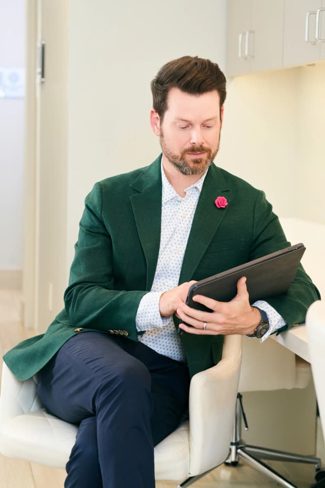 Liquid Facelift: Dr. Bader sitting and writing on his tablet