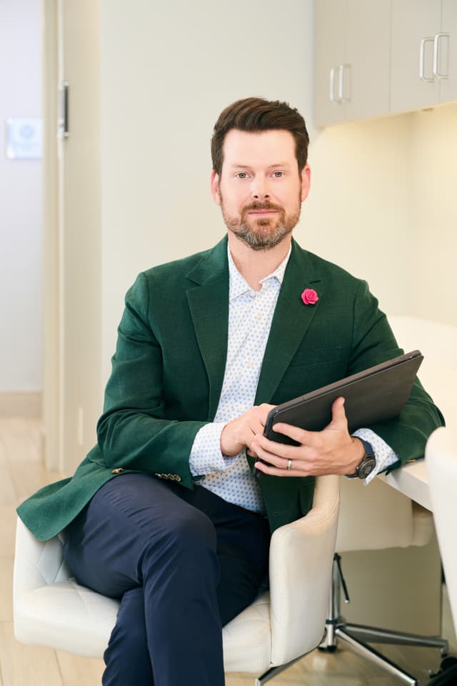 Microneedling In Dallas: Dr. Bader sitting and writing on his tablet