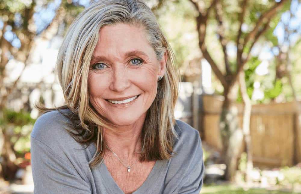 Smiling mature woman with natural facial rejuvenation results, reflecting expertise of a deep plane facelift surgeon in Dallas