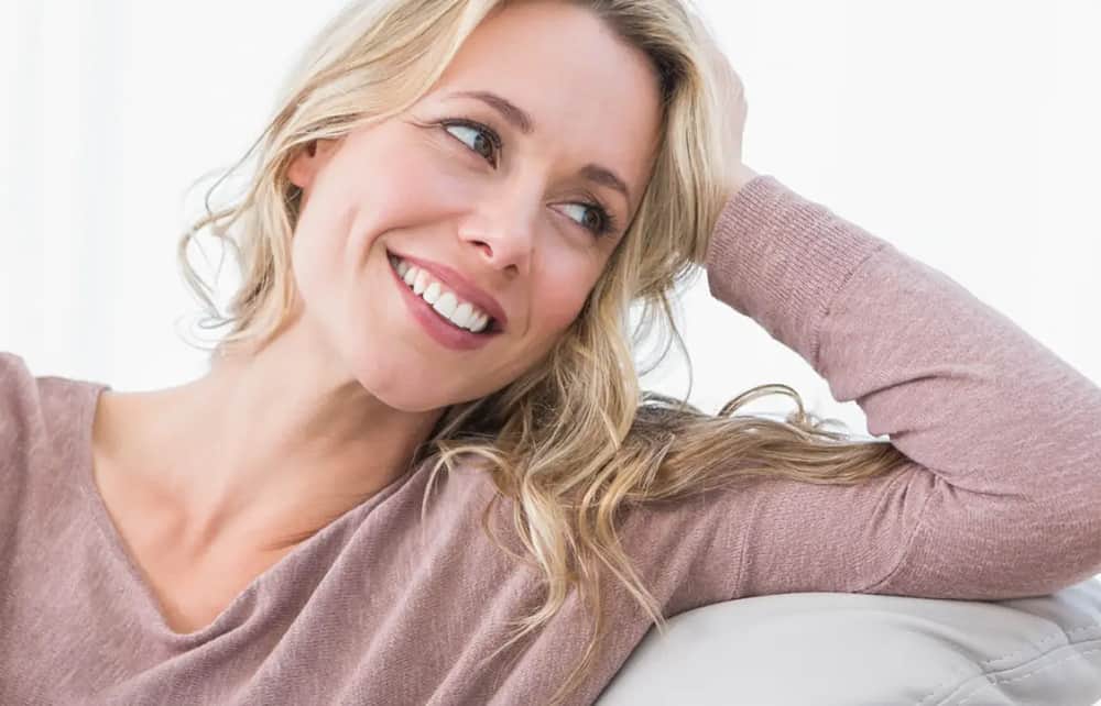 Smiling woman with smooth, natural-looking facial rejuvenation results reflecting expertise of a deep plane facelift surgeon in Dallas