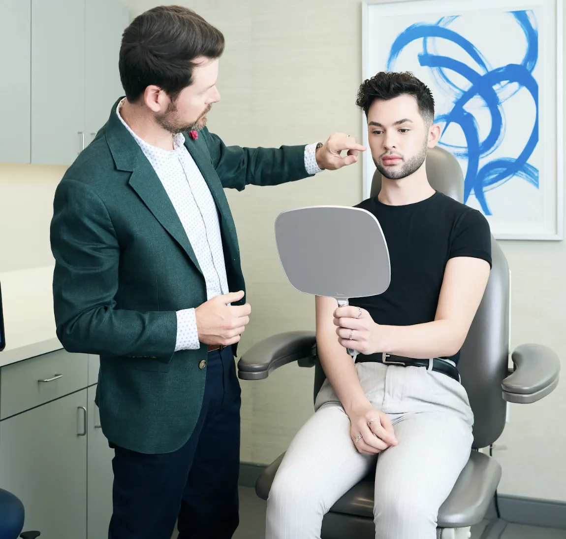 Nose evaluation: Surgeon reviewing nasal shape with a young patient using a handheld mirror