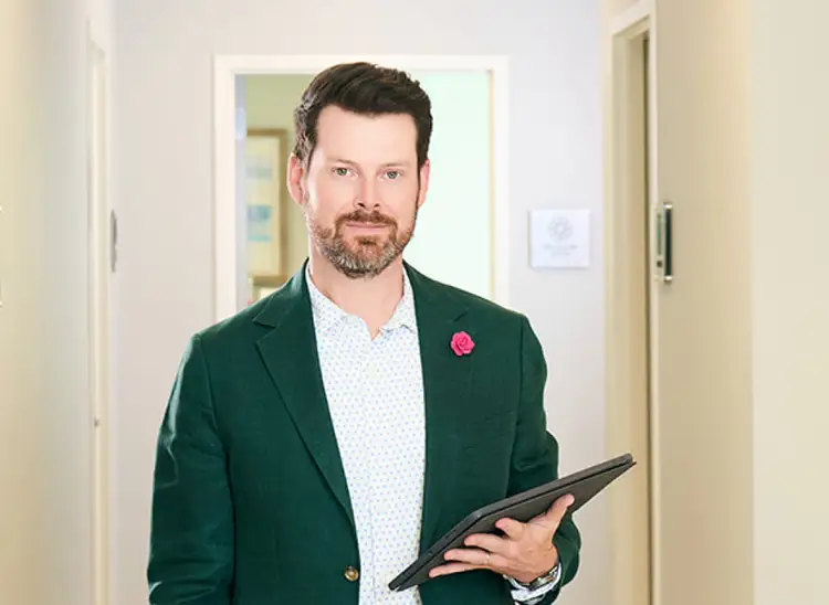 Expert deep plane facelift surgeon in Dallas seated in a modern consultation room, highlighting experience and refined facial rejuvenation care