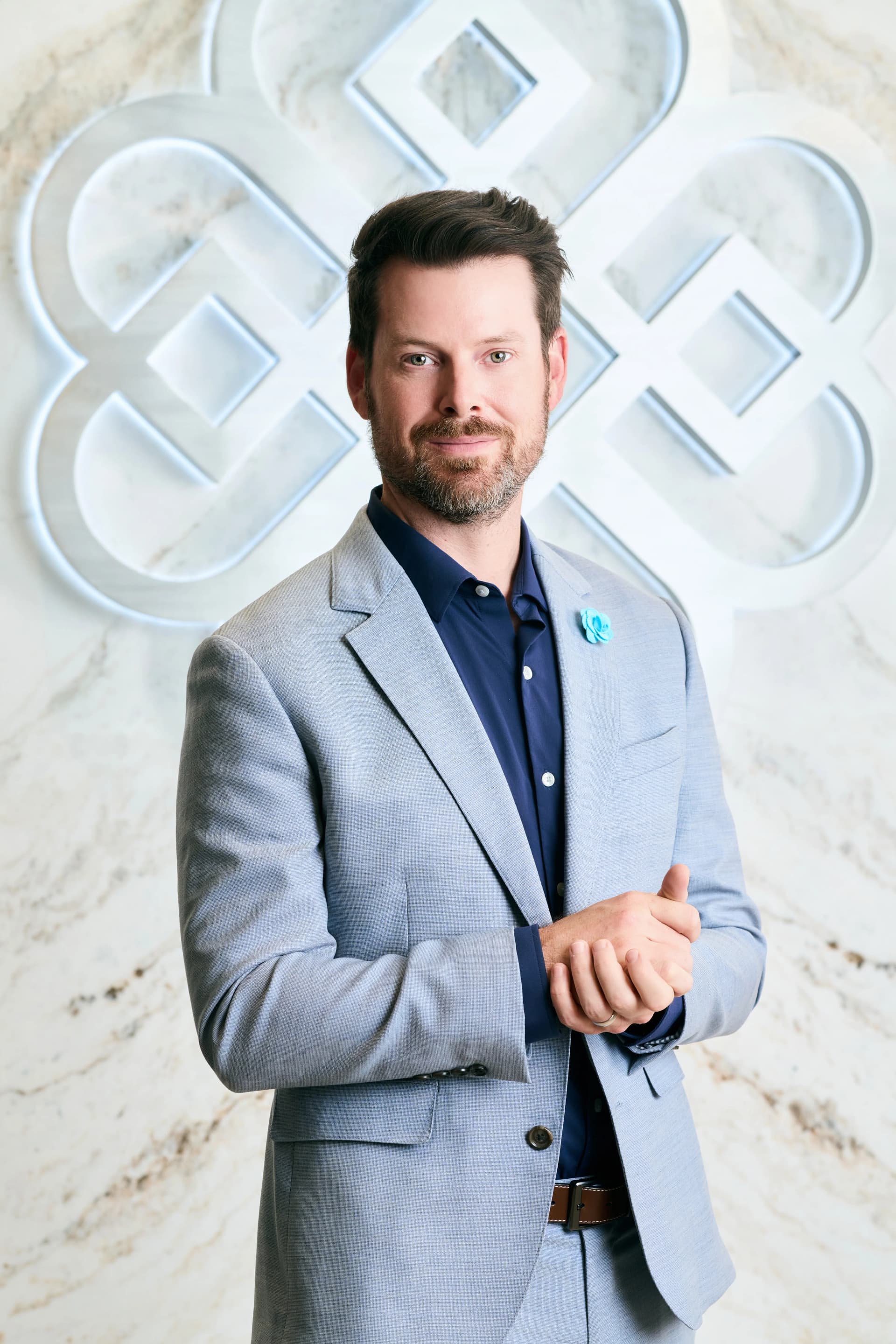 Nasal tip reduction: Dr. Bader standing in front of his logo at the clinic