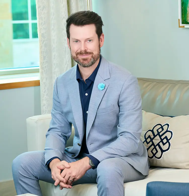 Expert deep plane facelift surgeon in Dallas seated in a modern consultation room, highlighting experience and refined facial rejuvenation care