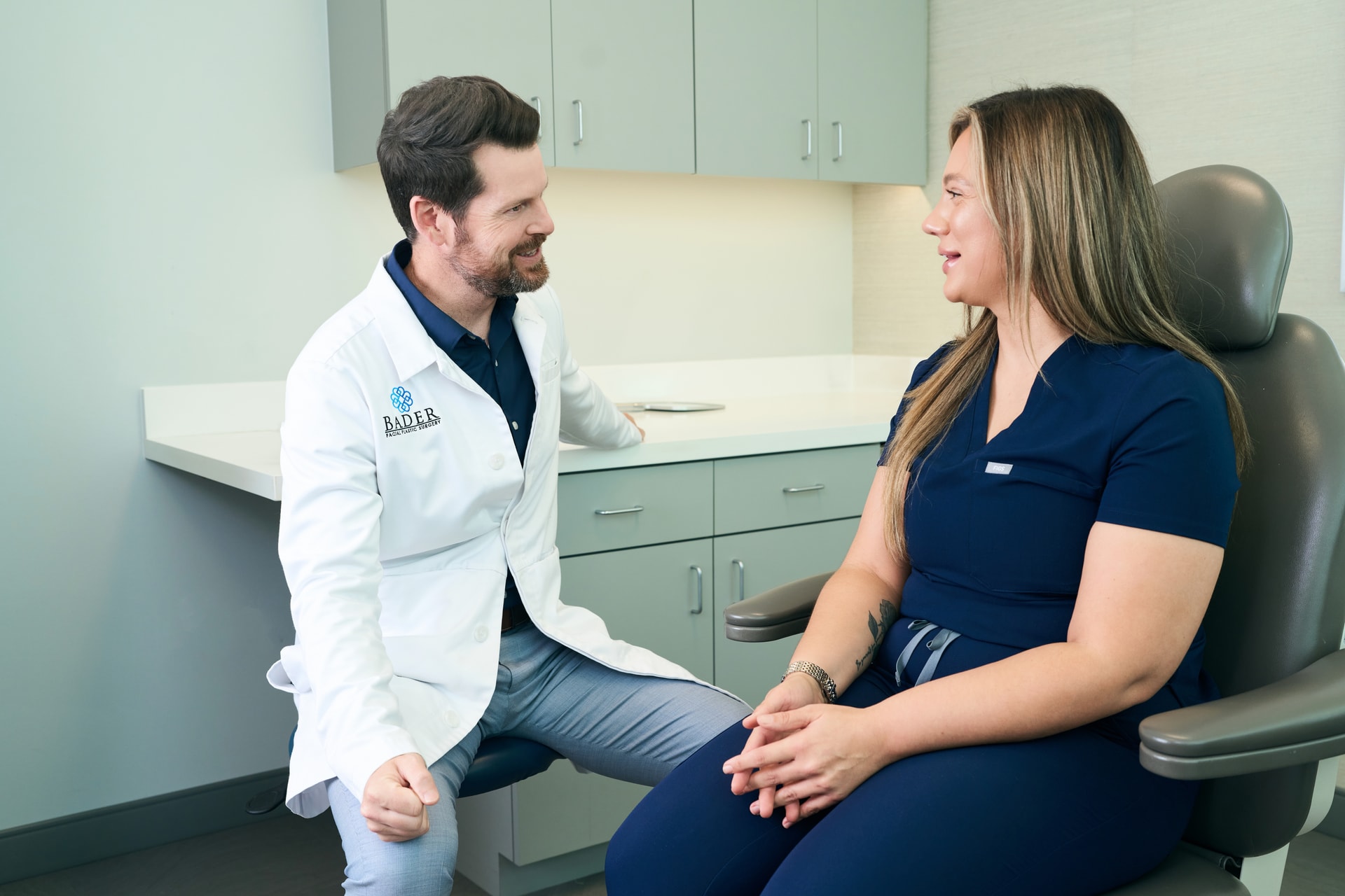 Microneedling In Dallas: Dr. Bader and young female patient discussing procedure in his office