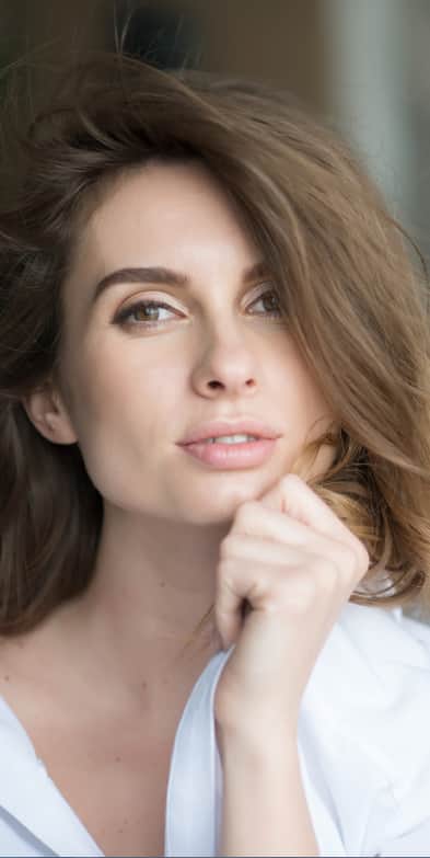 Woman touching nose and jawline showing facial profile before deviated septum surgery consultation in Plano and Dallas